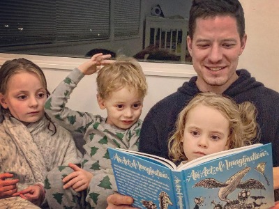Albin Sikora reading a book for three children.